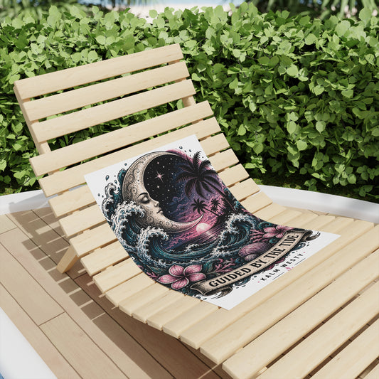 Beach towel on a wooden lounge chair featuring a crescent moon, tropical waves, and palms at sunset with boho art.