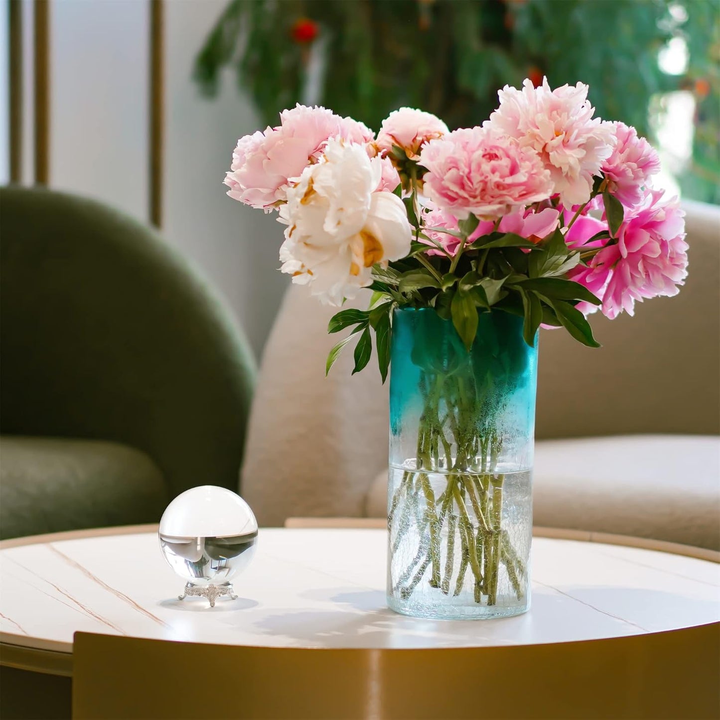 80mm clear K9 crystal ball on a silver ornate stand, displayed on a coffee table next to a vase of pink peonies.