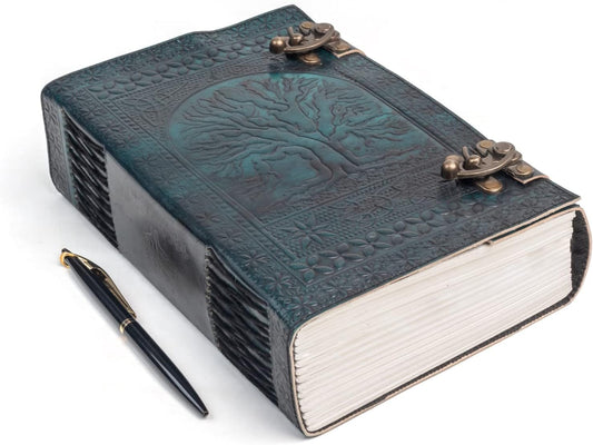 Handmade teal leather journal with embossed Tree of Life, antique metal clasps, and a black pen on a white background.