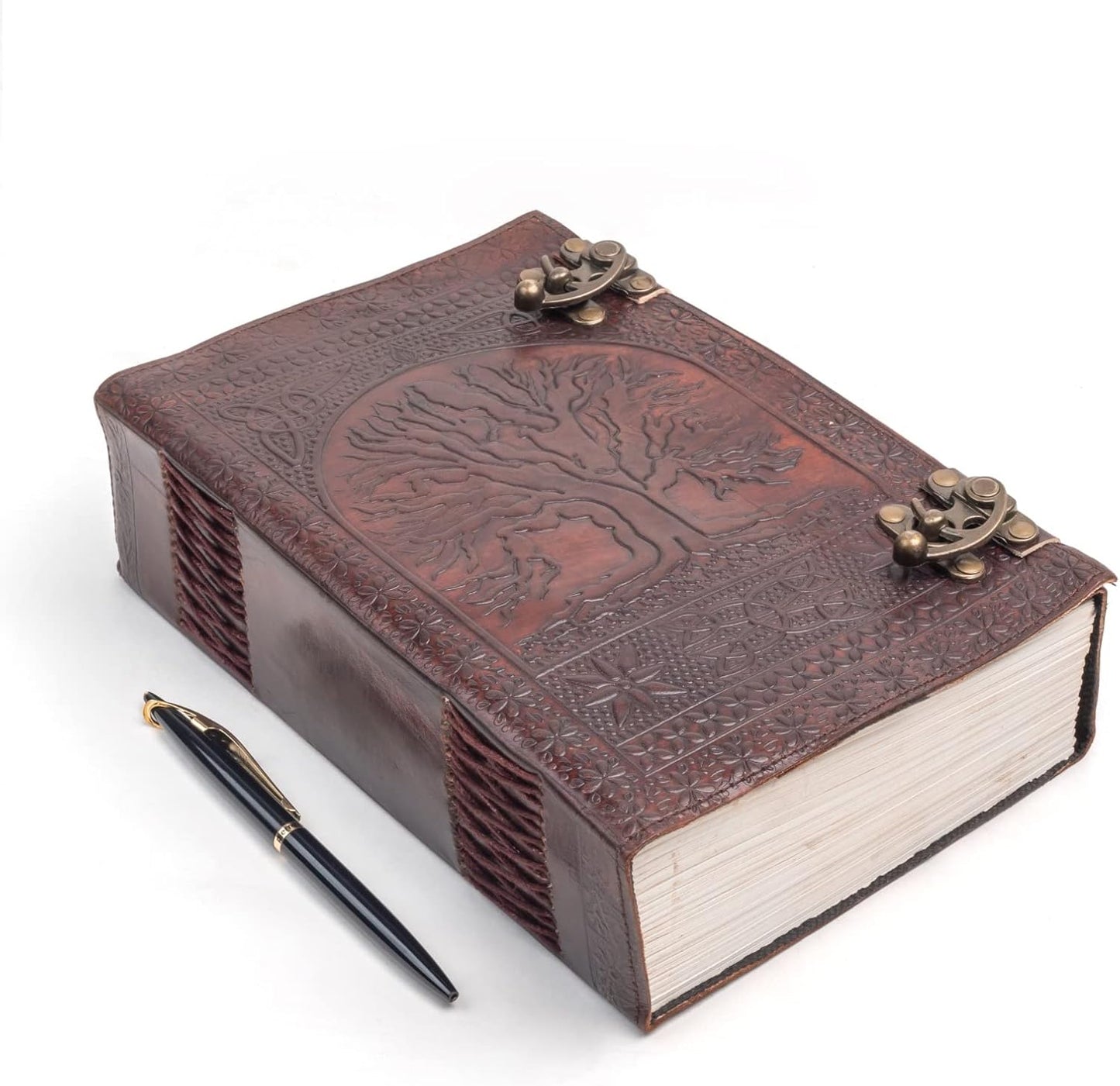 Brown handmade leather journal with embossed Tree of Life, brass C-locks, and hand-stitched binding beside a black pen.